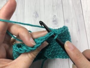 hands holding green yarn and crochet hook