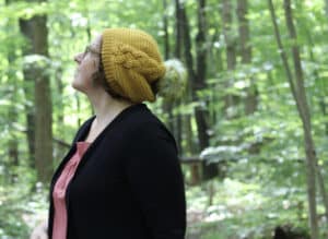 yellow hat white pompom worn by woman in forest