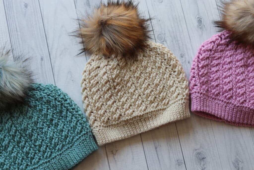 three crochet hats displayed on an angle in three different colours