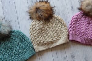 three crochet hats displayed on an angle in three different colours