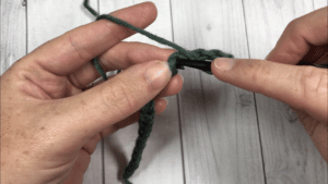 hands crocheting with green yarn