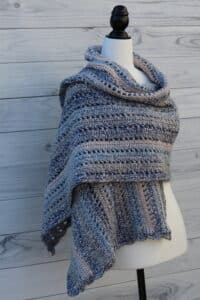 Crochet shawl in blue draped over a mannequin