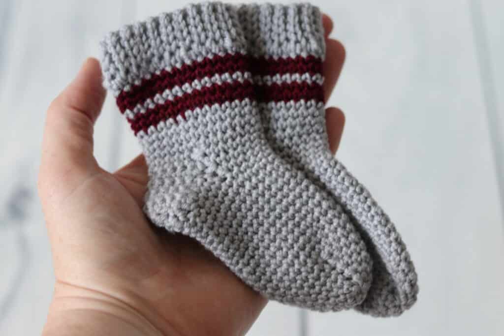 hand holding baby sized pair of crochet socks