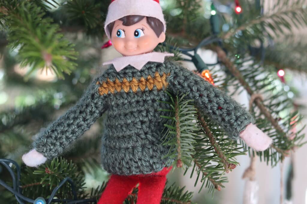 A Christmas Elf in a green and gold crochet sweater