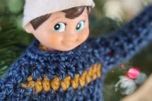 close up of a blue crochet sweater on an elf