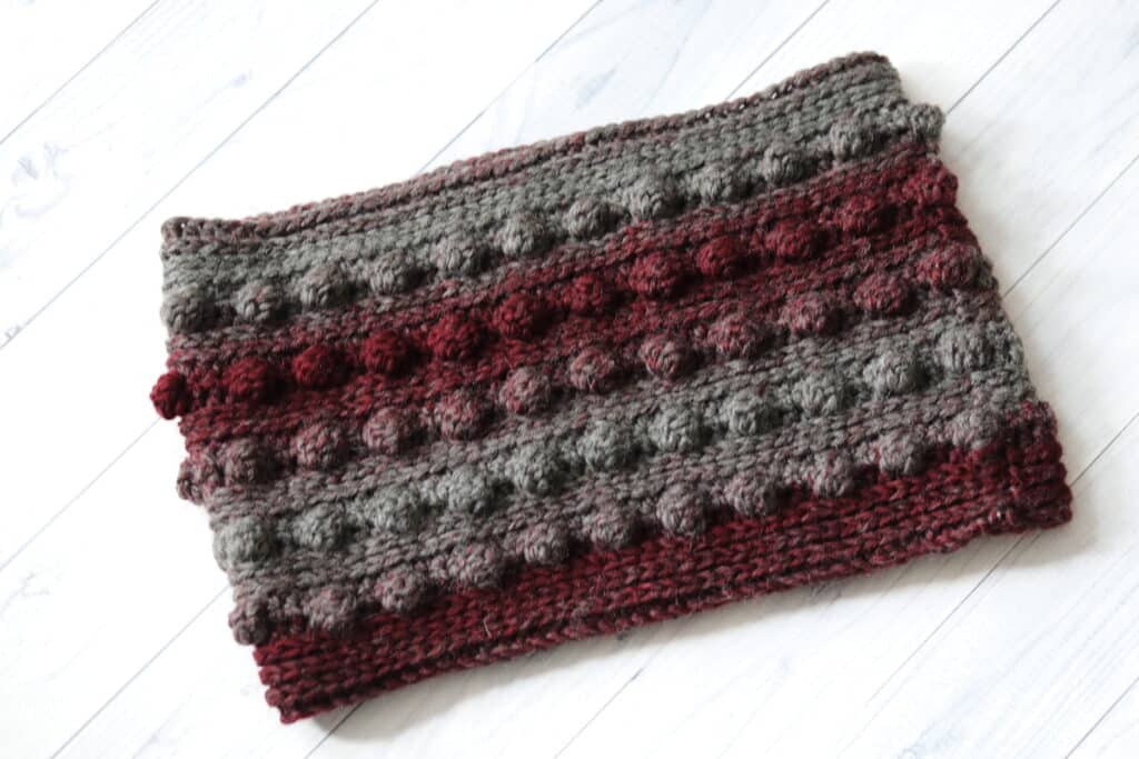 A red and grey textured crochet cowl featuring rows of bobble stitches
