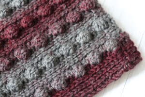 a close up of a red and grey textured crochet cowl