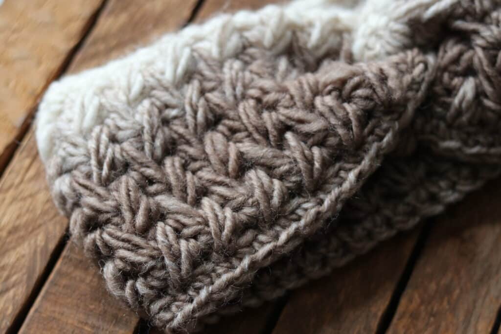A Close up of a crochet twisted ear warmer worked in the feather stitch