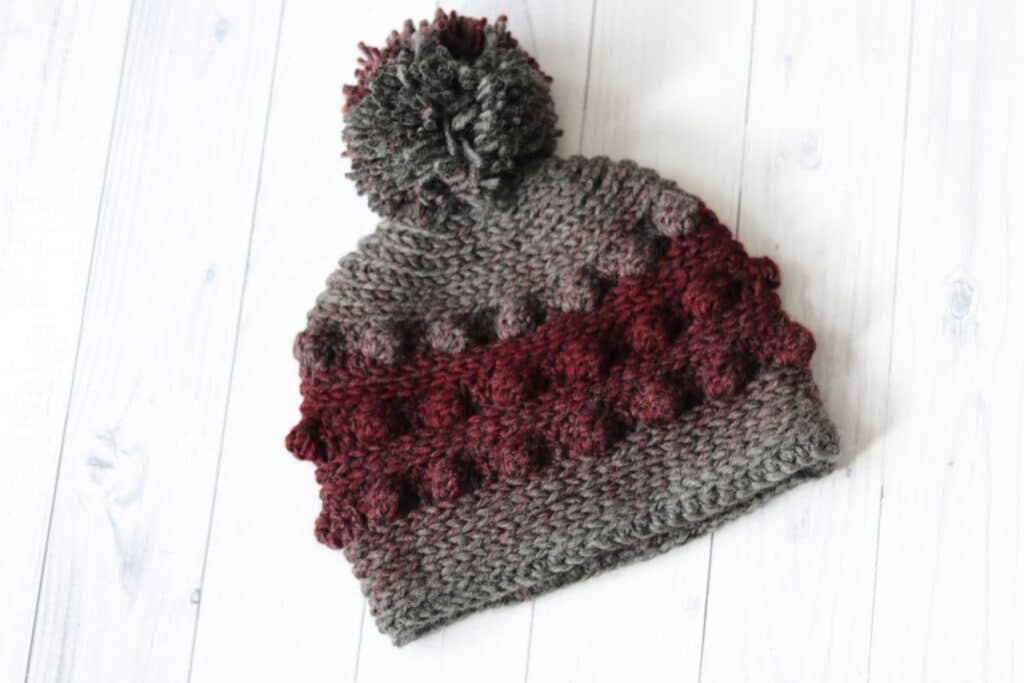 A grey and red crochet beanie featuring bobble stitches