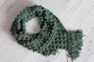 a green textured crochet scarf with bobble stitches