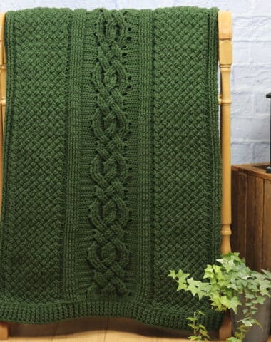 A cable textured crochet blanket worked in green yarn