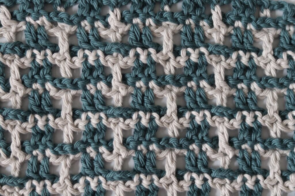 A crochet fabric in green and grey yarn that looks like it is woven