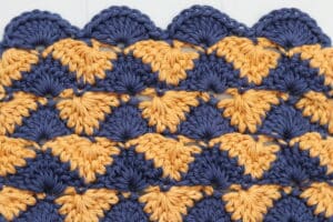 A sample of the summer shells crochet stitch worked in blue and gold yarn