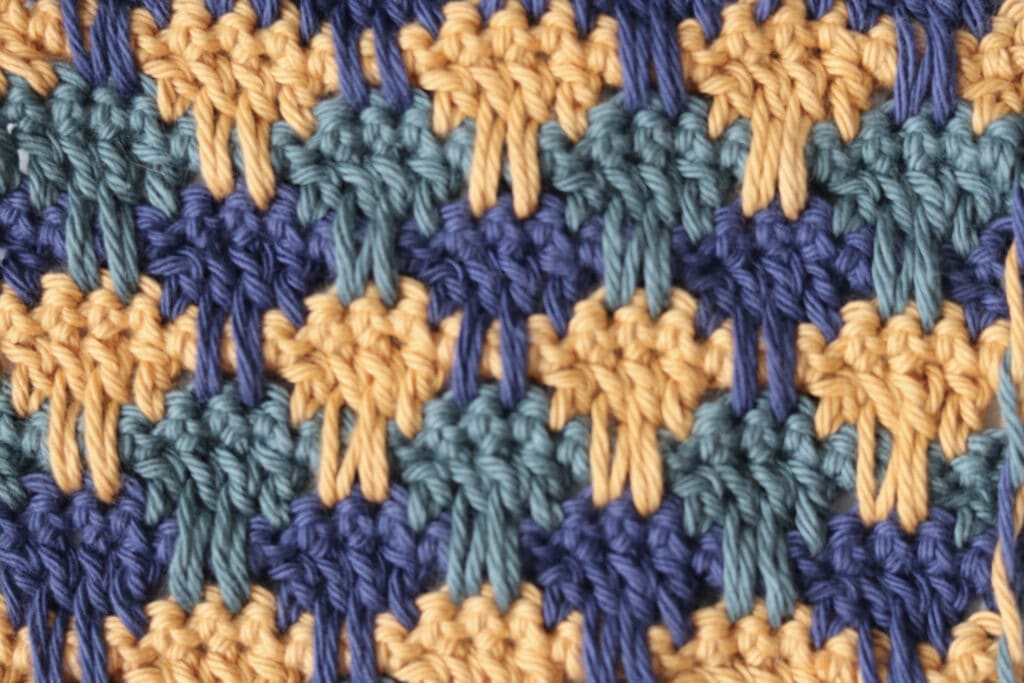 The Crochet Flame Stitch worked in blue, gold and green yarn