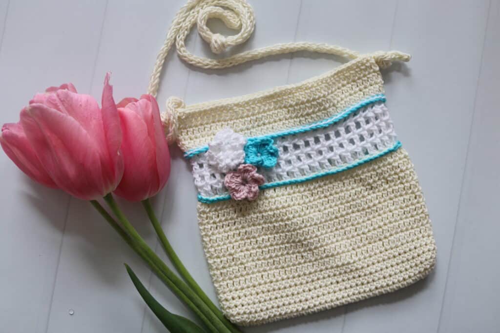A crochet pattern for a children's purse featuring three small flowers