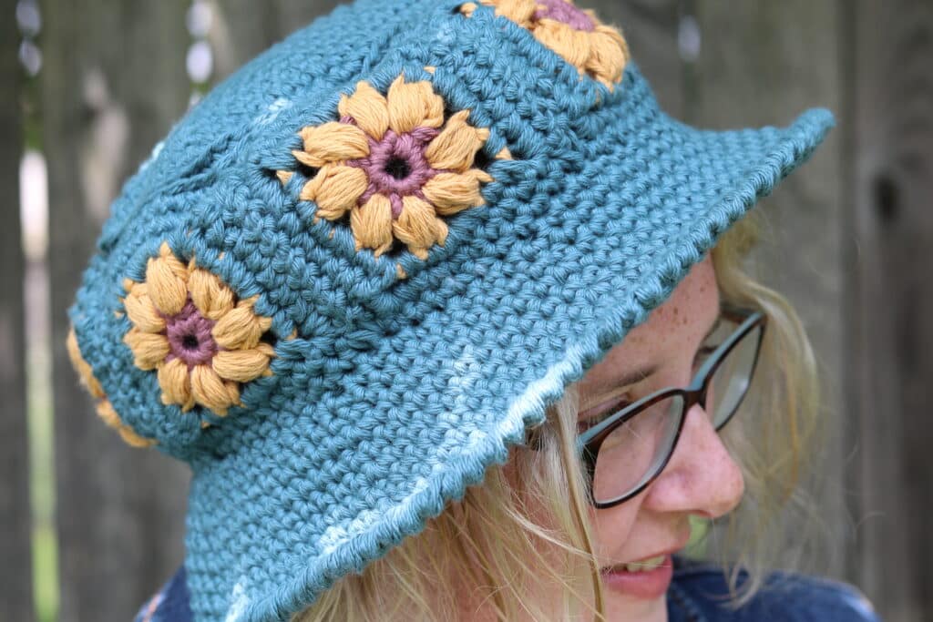 A teal crochet bucket hat with yellow flowers