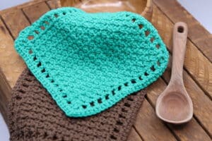 Two crochet washcloths, one worked in green yarn and another worked in brown yarn