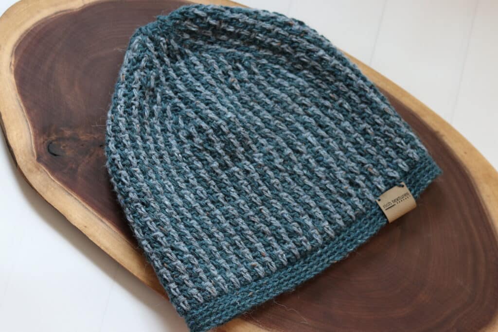 The Crochet Cabin Beanie worked in a green and grey yarn