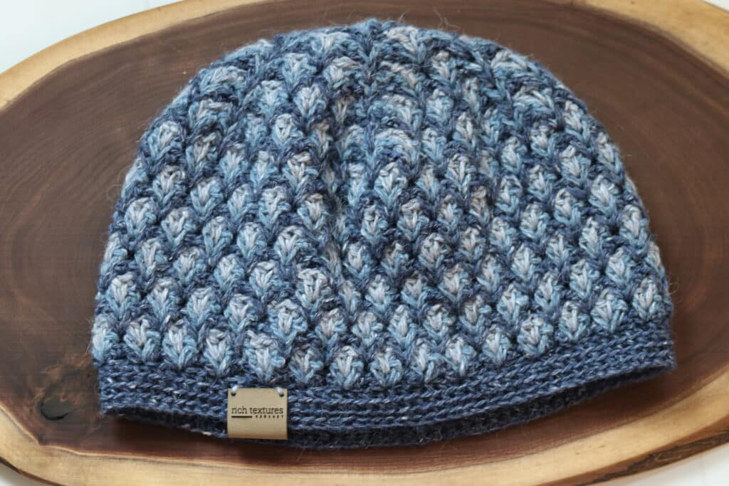 A Crochet Hat featuring three different shades of blue yarn