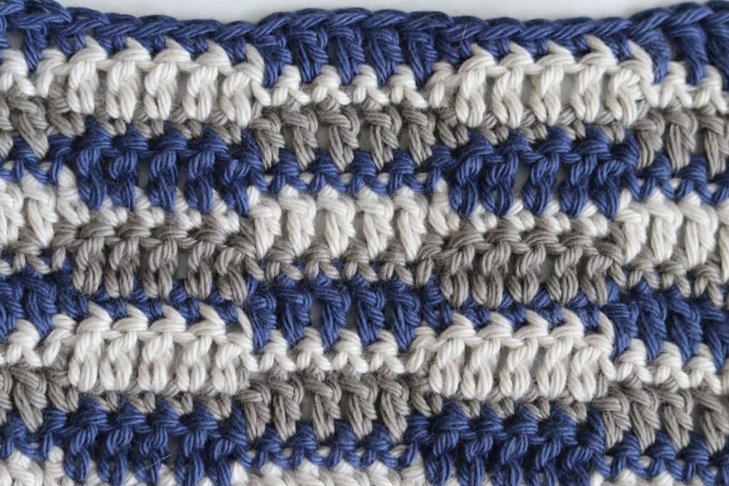 A swatch of the crochet checkered stitch worked in blue, white and grey yarn