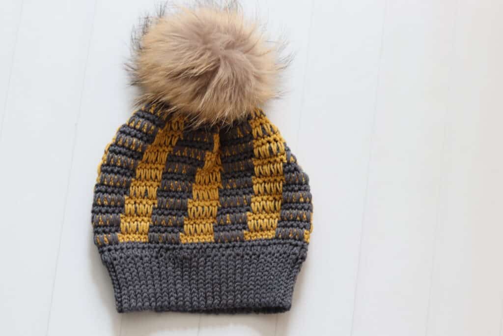 A grey and gold crochet beanie featuring spike stitches