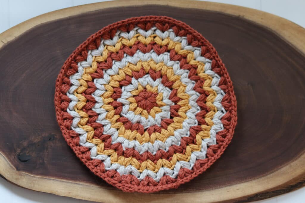 A round crochet washcloth featuring puff stitches