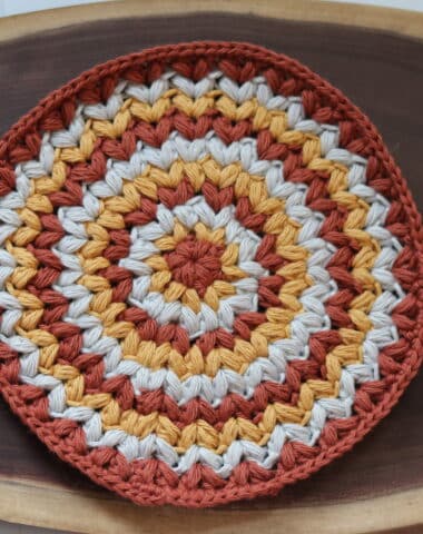 A round crochet washcloth featuring puff stitches
