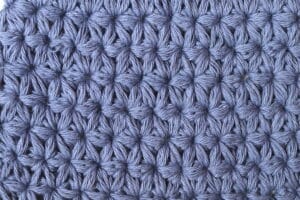 A swatch of the Jasmine Crochet stitch worked in a blue yarn