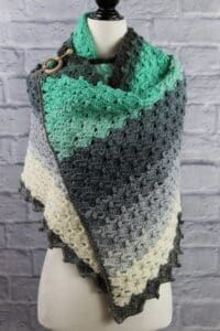 A rectangular crochet shawl featuring double crochet shell stitches and puff stitches