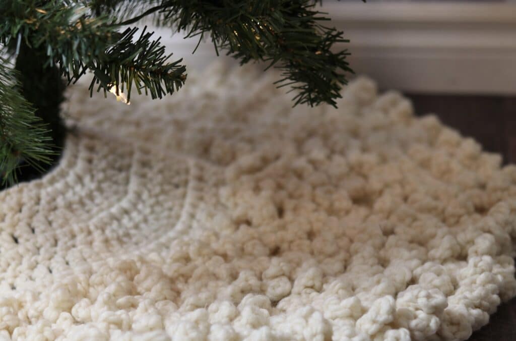 A close up of a crochet Christmas tree skirt under a Christmas tree