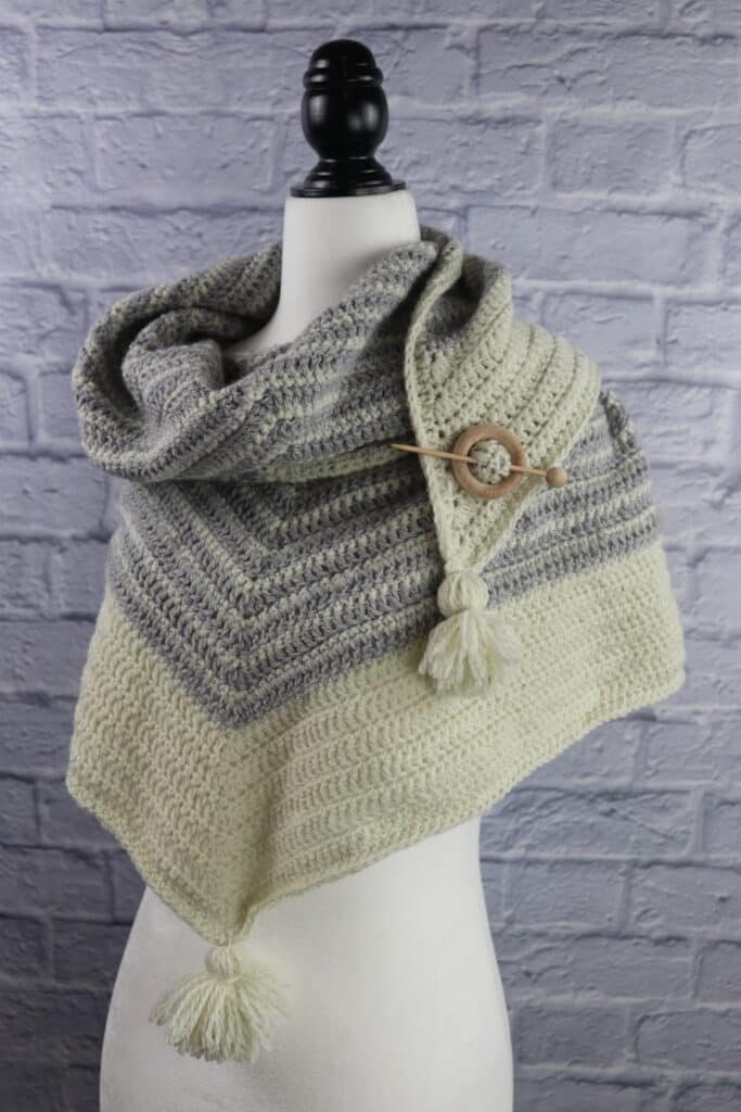 A grey and white stripped triangular crochet shawl