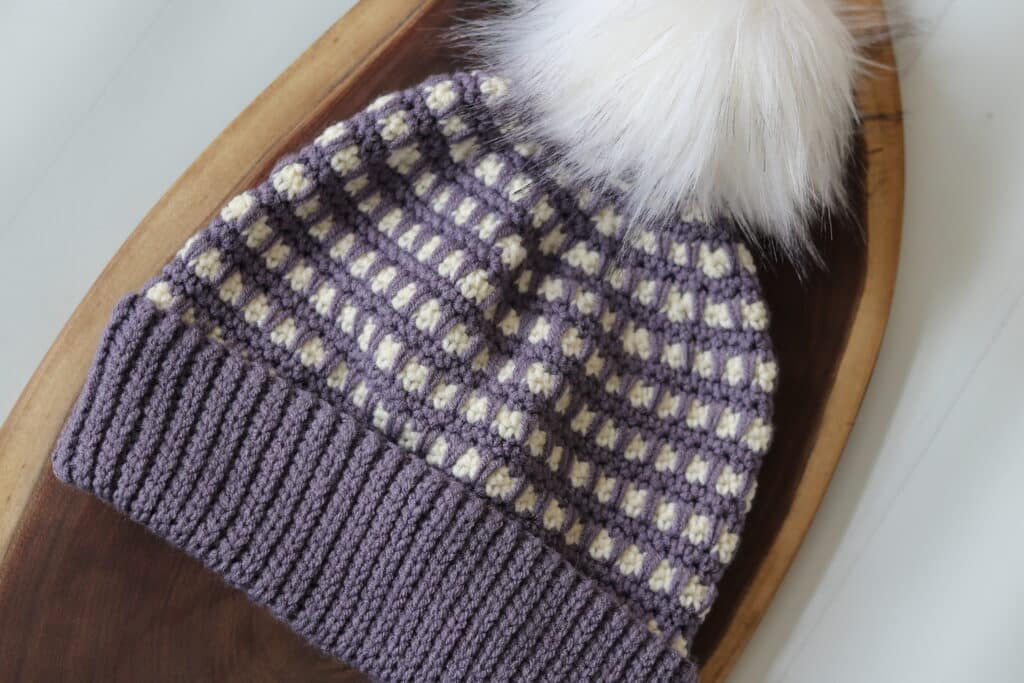 A purple and white crochet beanie