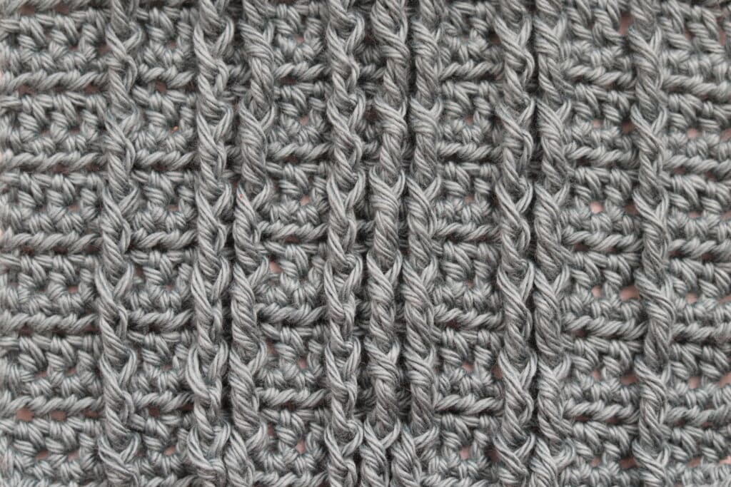 A Swatch of crochet straight cables worked in a grey coloured yarn