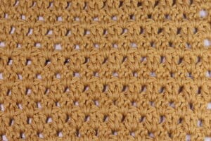 A swatch of the crochet Wide V Stitch worked in a golden coloured yarn