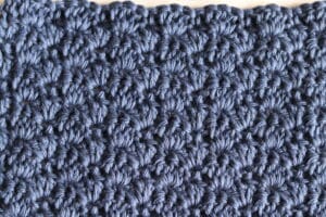 A swatch of the little shells crochet stitch worked in a blue yarn