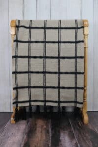 A tan coloured crochet blanket with black stripes
