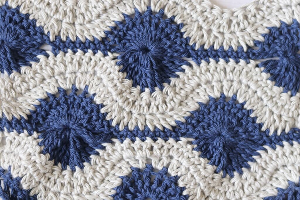 A circular crochet stitch pattern worked in grey and blue yarn