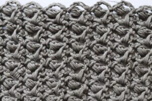 A swatch of the Little Rocks Crochet Stitch worked in a grey yarn