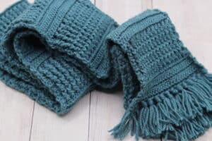 A textured crochet scarf crocheted in a teal coloured yarn
