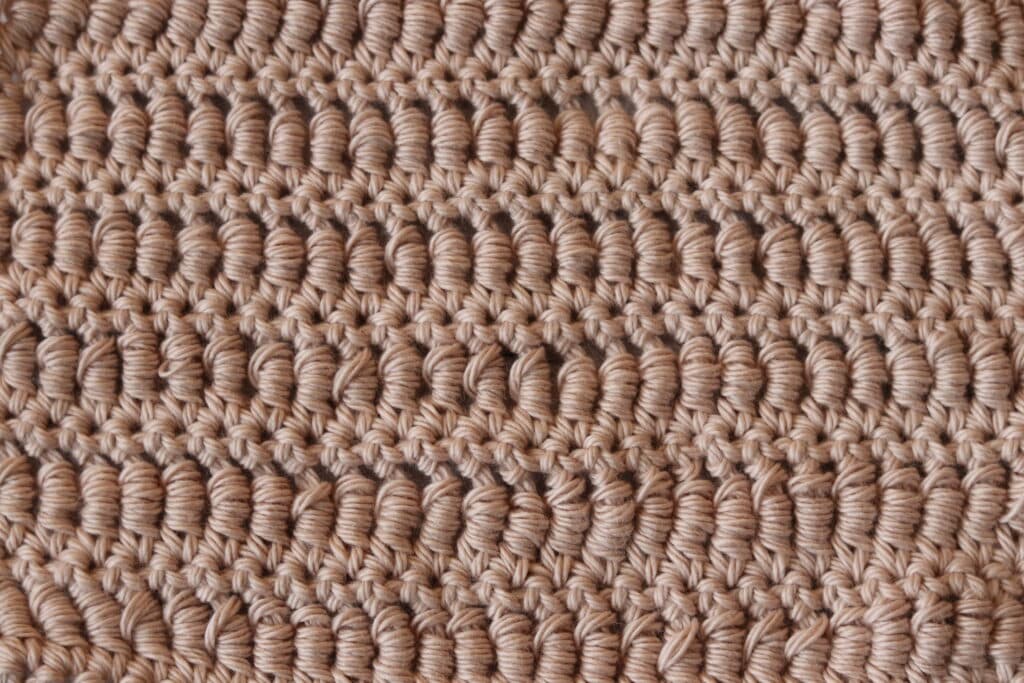 A swatch of the bouillon crochet stitch in a light pink yarn