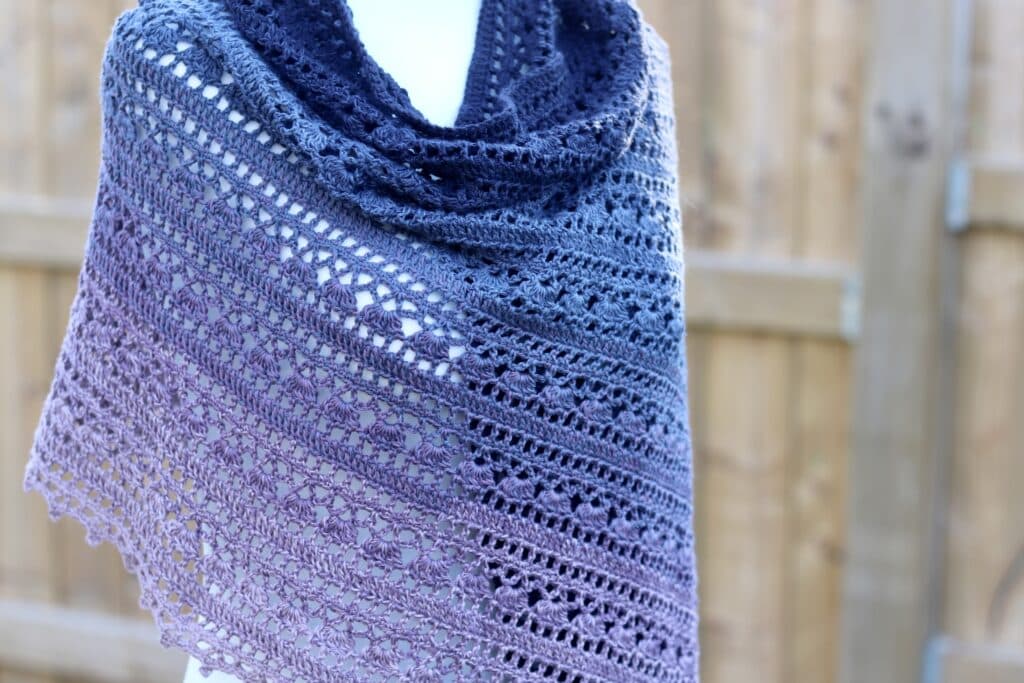 A lace crochet shawl featuring crochet cluster stitches