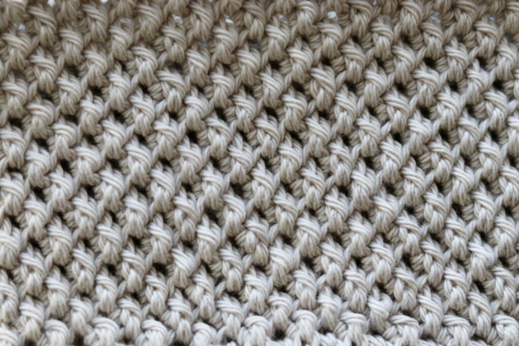 A swatch of a textured crochet stitch worked in a round in white yarn