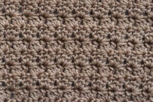 A swatch of the Slanted Clusters Crochet stitch worked in tan yarn
