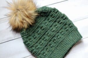 crochet Drew Beanie in green yarn with tan pompom