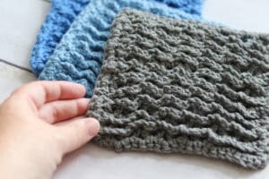 hand holding a grey textured crochet dishcloths