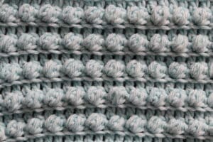 A swatch of the Pretty Puffs crochet stitch worked in a light blue yarn