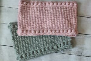 Two crochet neck warmers, one pink, one grey