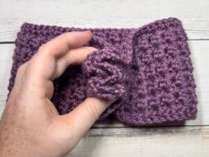 A demonstration of how to fold the two short ends of the ear warmer together