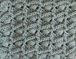 A swatch of the Slanted Puff Shell crochet stitch worked in green yarn
