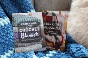 Barn Quilt Blankets and Comfy and Cozy Crochet Blanket books displayed on a couch with a blue striped blanket